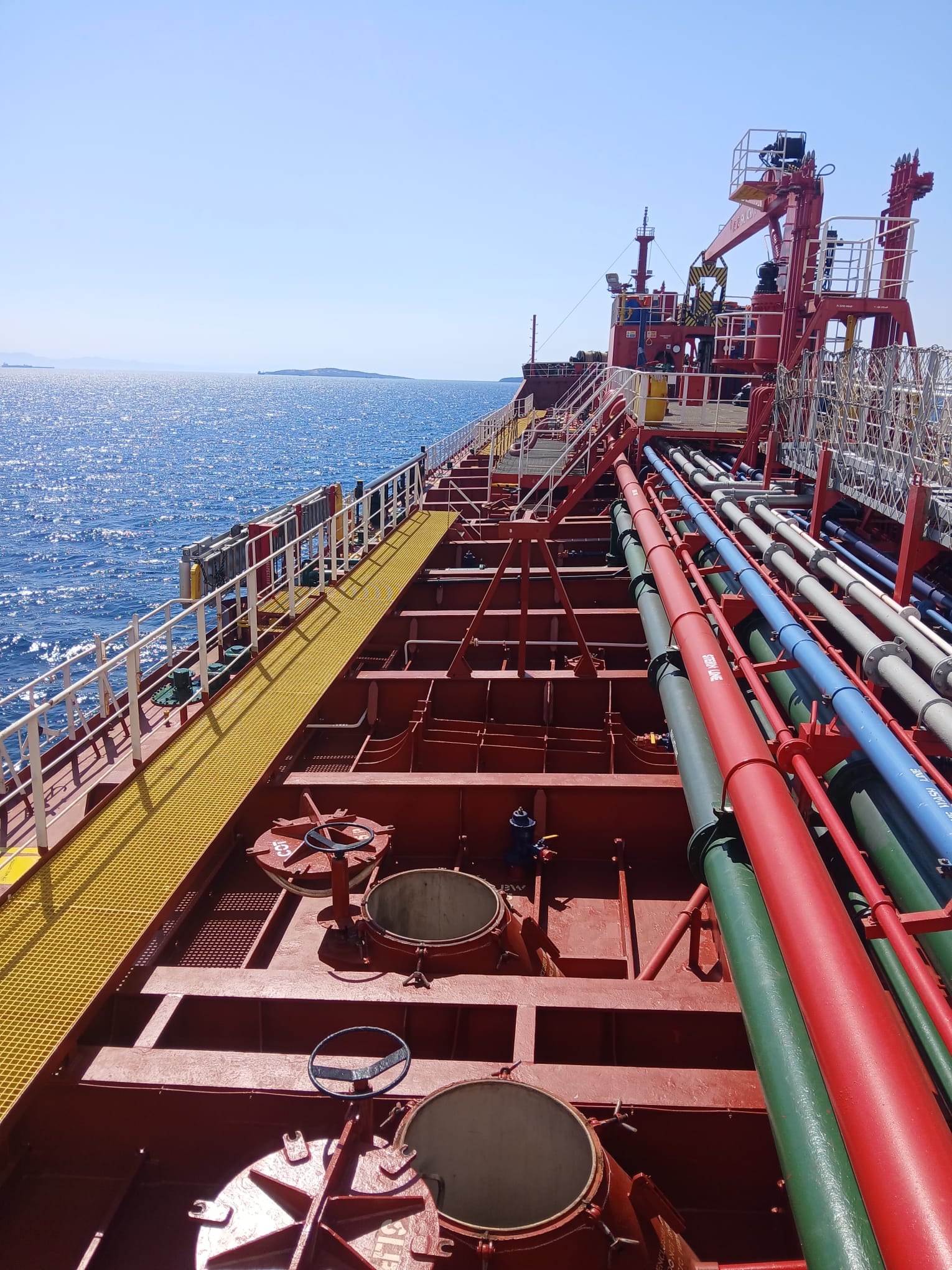 Open tank hatches and pipework on a tanker deck on a sunny day